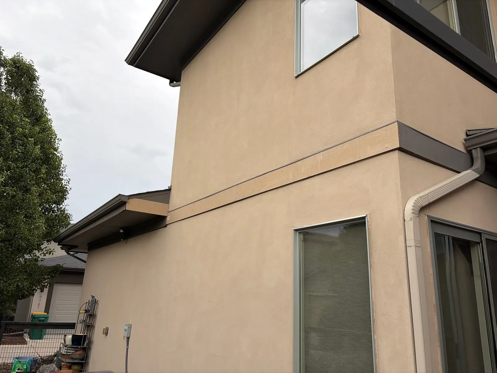 Freshly replaced wood trim board at a stucco corner during siding repair on a north Denver home